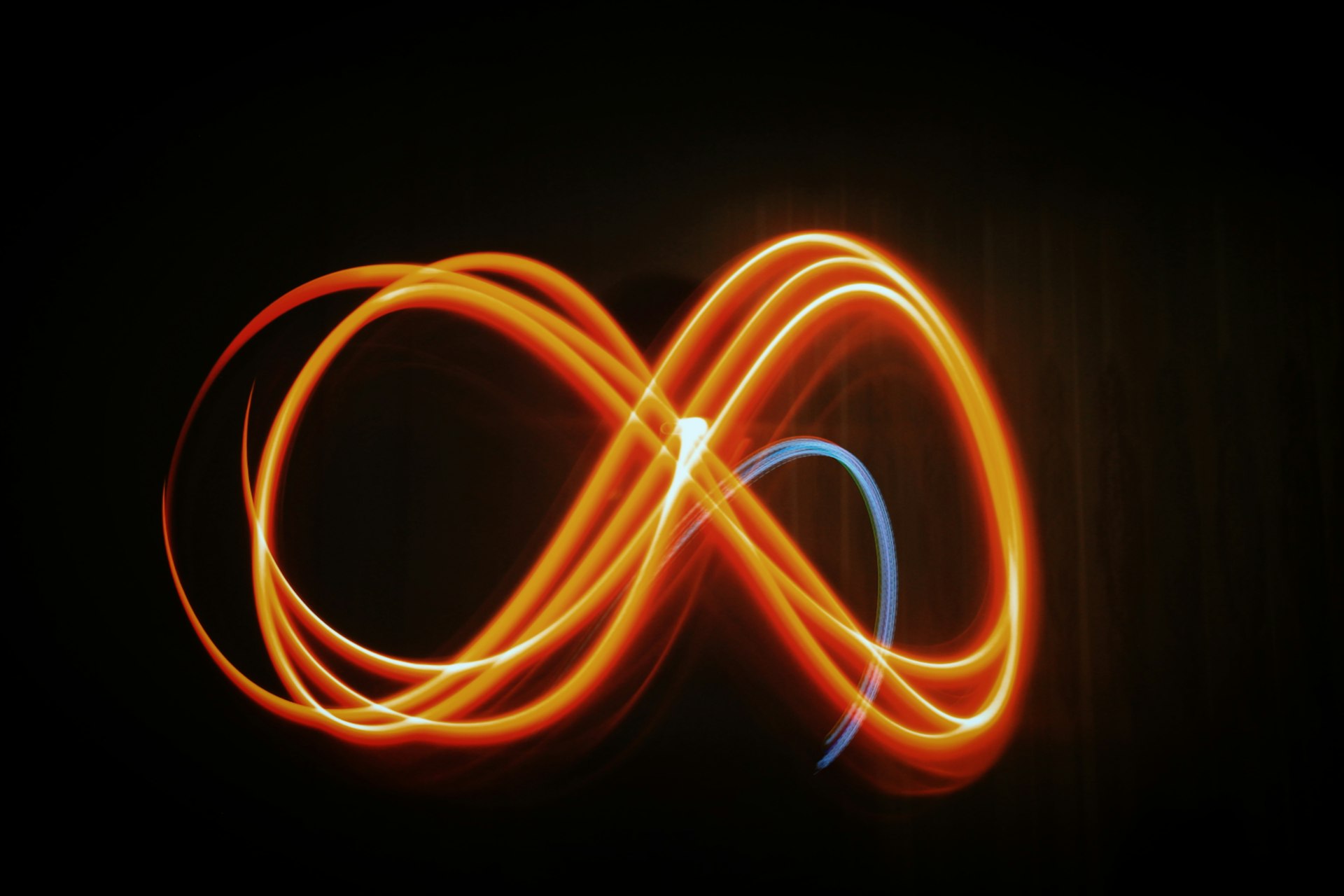 Infinity symbol representing Sign Architects' commitment to excellence, sustainability, and service Abstract infinity symbol with glowing orange and blue light trails representing excellence and sustainability